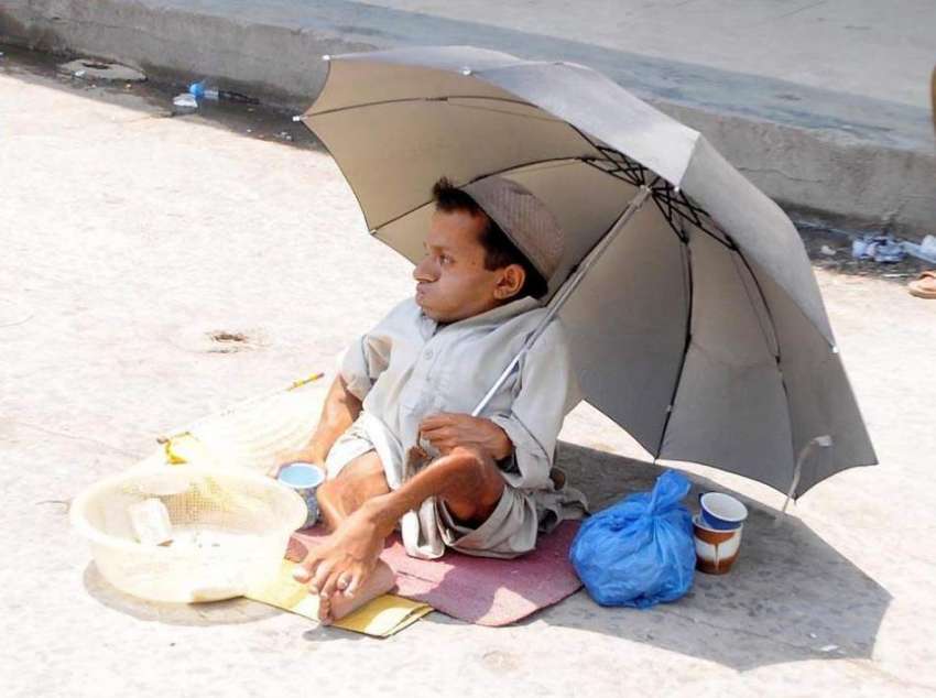 راولپنڈی: ایک معذور شخص مری روڈ پر چھتری تانے بھیک مانگ رہا ..