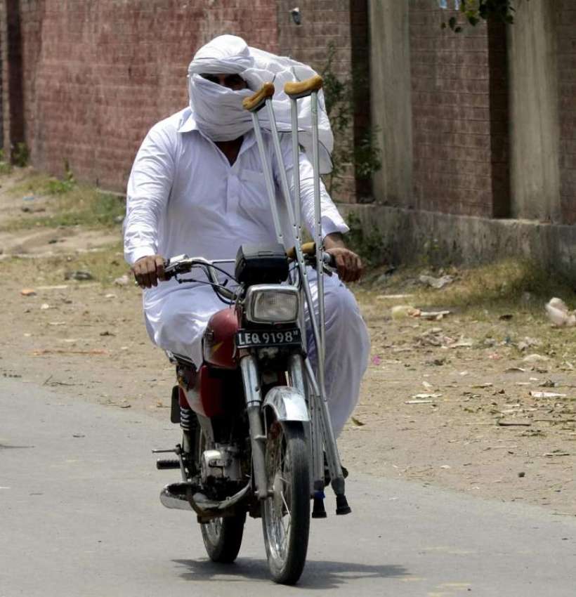 لاہور: ایک معذور شخص موٹر سائیکل پر اپنی منزل کی طرف گامزن ..