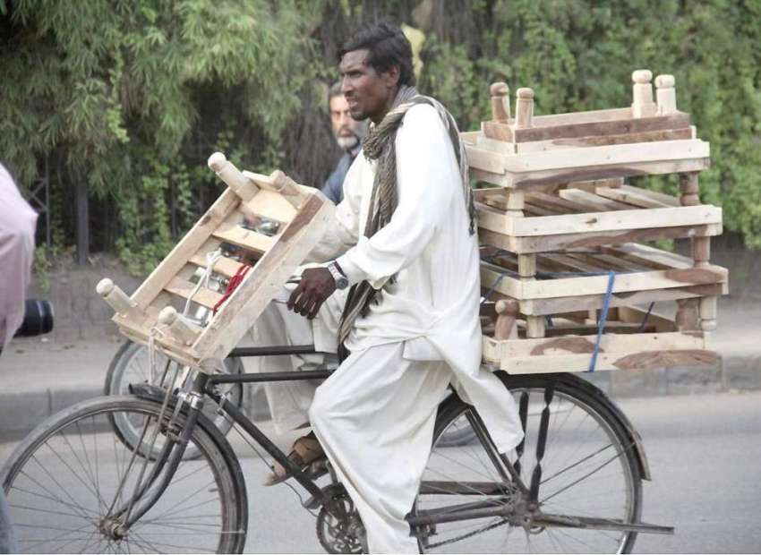 لاہور: ایک سائیکل سوار محنت کس لکڑی کی چوکیاں فروخت کے لیے ..