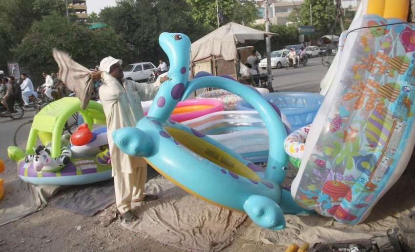 لاہور: ایک محنت کش سڑک کنارے فروخت کے لیے رکھے پلاسٹک کے ..