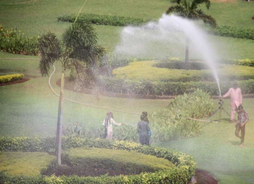 لاہور: پی ایچ اے کا ملازم پارک میں پانی لگا رہا ہے جبکہ بچے ..