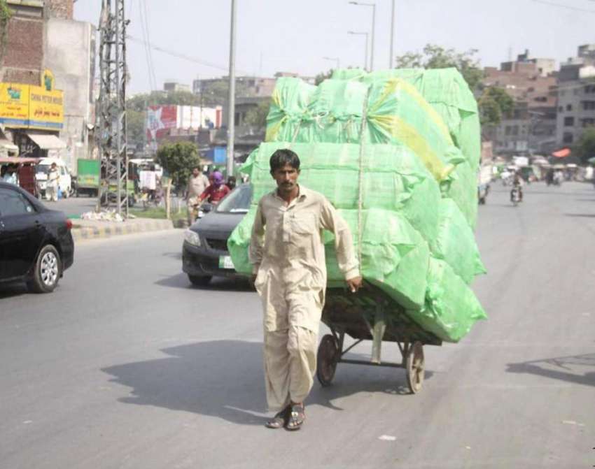لاہور: ایک محنت کش ہتھ ریڑھی پر بھاری سامان رکھے جا رہا ہے۔