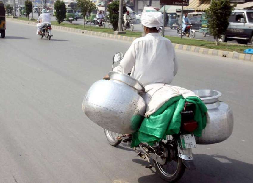 لاہور: ایک شخص موٹر سائیکل پر خطر ناک انداز سے دیگیں رکھ ..