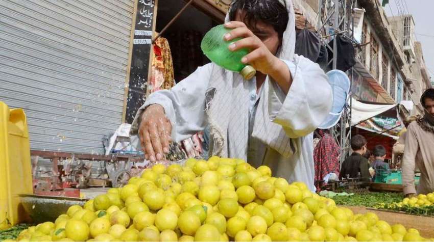 کوئٹہ: سبزی منڈی میں ایک ریڑھی بان لیموں پر پانی چھڑک رہا ..