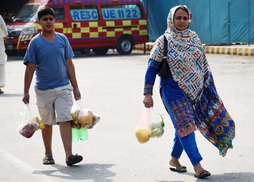 لاہور: خاتون بچے کے ہمراہ سستا رمضان بازار سے افطاری کے لیے ..