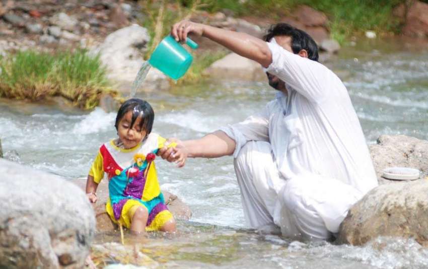 اسلام آباد: ایک شخص اپنی بچی کو گرمی کی شدت سے بچانے کے لیے ..