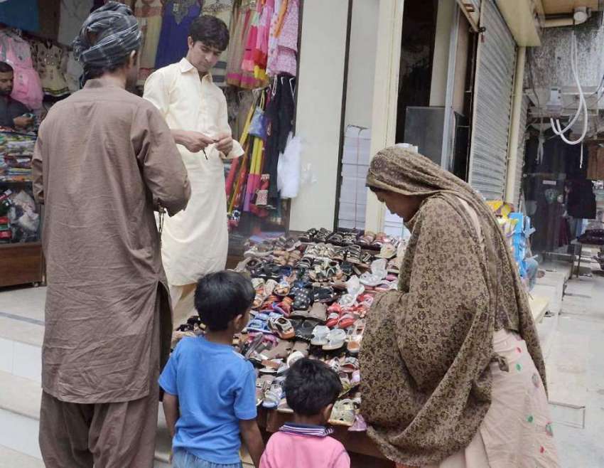 کوئٹہ: عبدالستار روڈ پر ایک خاتون بچوں کے لیے چپلیں خرید ..