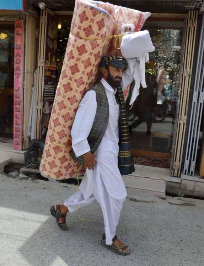 کوئٹہ: لیاقت بازار میں ایک شخص عید کے لیے فوم کندھوں پر اٹھائے ..