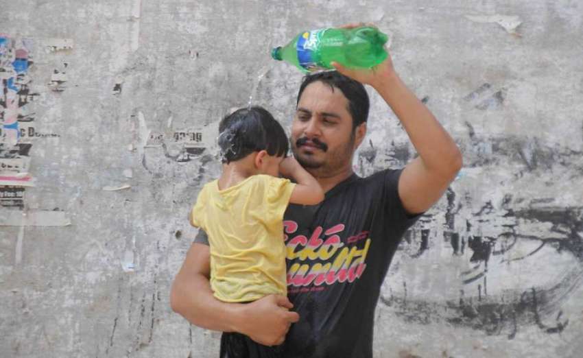 راولپنڈی: گرمی کی شدت کم کرنے کے لیے ایک شخص بچے کے سر پر ..