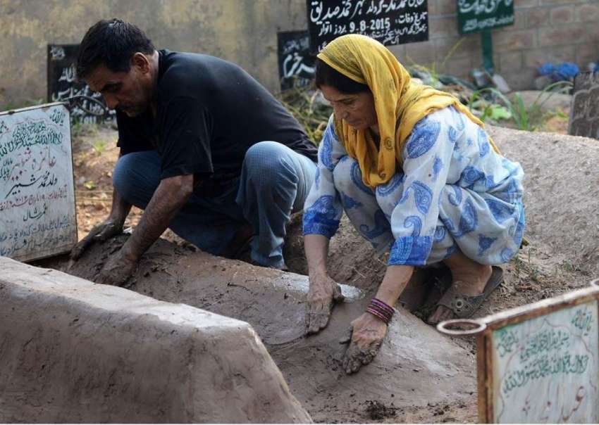 لاہور: عید الفطر کی آمد کے موقع پر قبرستان میں ایک فیملی ..