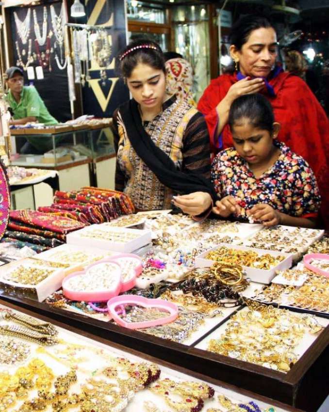 کراچی: عید کی تیاریوں میں مصروف خواتین اور بچے ایک اسٹال ..