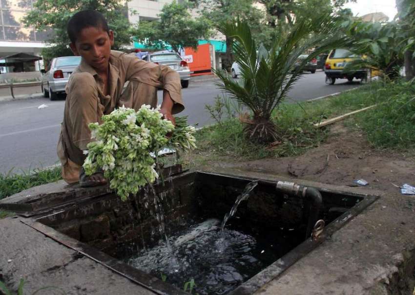اسلام آباد: ایک لڑکا گلدستہ بنانے سے قبل پھولوں کو دھو رہا ..