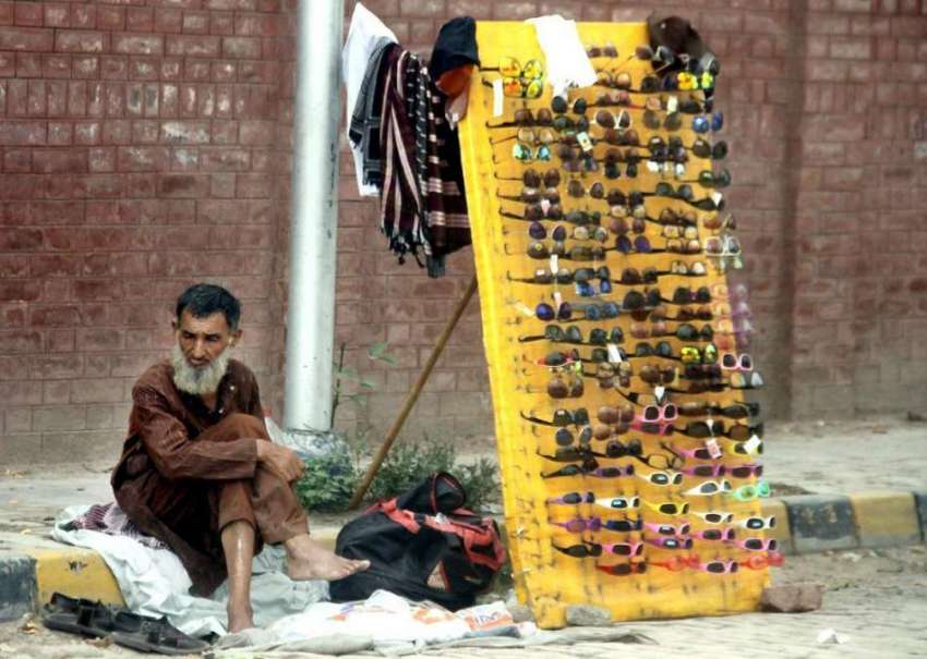 لاہور: ایک محنت کش سڑک کنارے چشموں کی دوکان سجائے گاہکوں ..