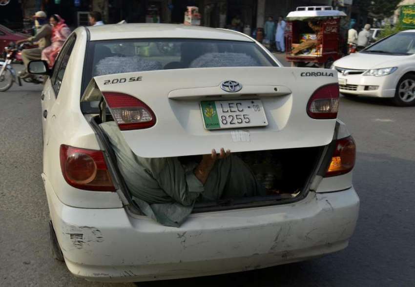 فیصل آباد: ایک شخص کار کی ڈگی میں بیٹھ کر سفر کر رہا ہے۔