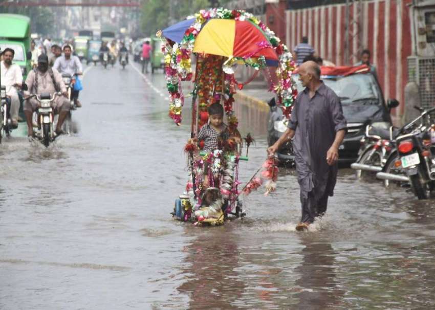 لاہور: ایک دوکاندار بارش کے دوران ایک شخص منفرد انداز میں ..