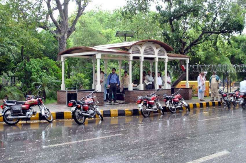 لاہور: صوبائی دارالحکومت میں بارش کے دوران شہری سڑک کنارے ..