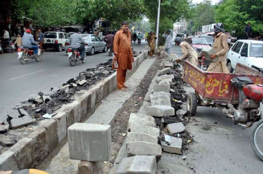 لاہور: فاطمہ جناح روڈ پر مزدور سڑک کنارے سیمنٹ کے بلاک لگانے ..