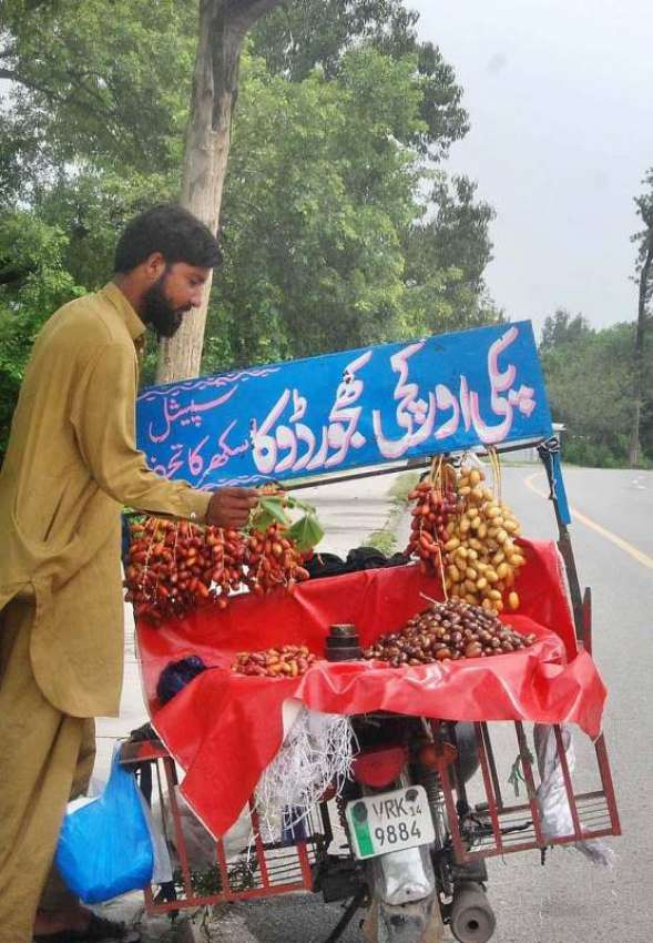 اسلام آباد: ایک محنت کش فروخت کے لیے موٹر سائیکل پر کھجوریں ..