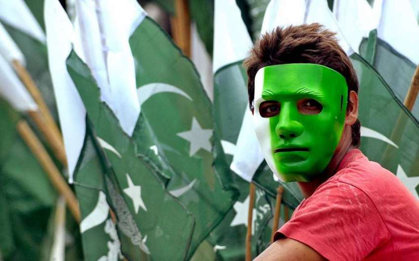 راولپنڈی: نوجوان محنت کش پاکستانی پرچم نما ماسک پہنے روڈ ..
