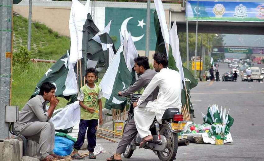 اسلام آباد: یوم آزادی کی آمد کے موقع پر ایک محنت کش روڈ کنارے ..