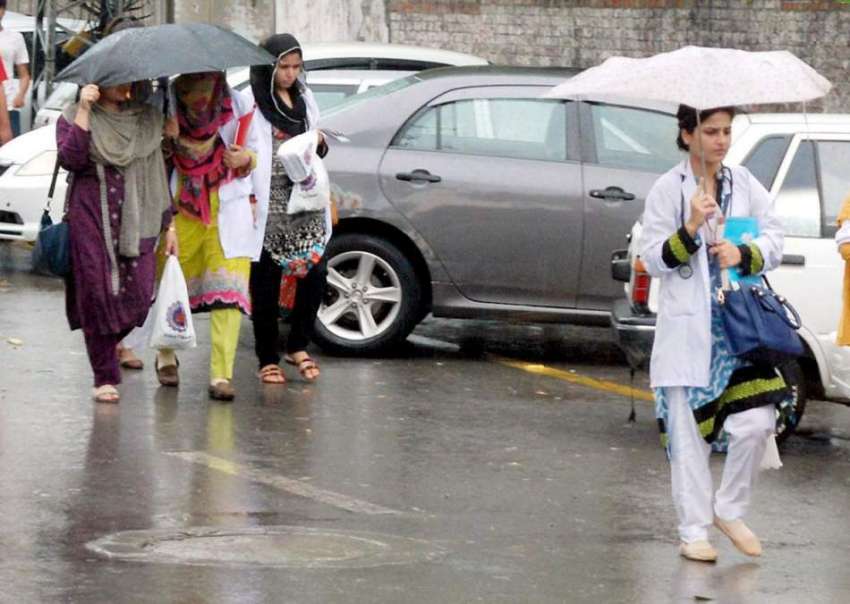 لاہور: میڈیکل کی طالبات بارش سے بچنے کے لیے چھتریاں تانے ..