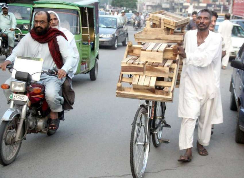 لاہور: ایک محنت کش لکڑی کی تیار چوکیاں فروخت کرنے کے لیے ..