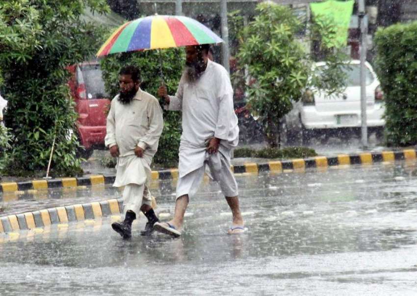 لاہور: شہر میں ہونیوالی بارش کے دوران دو شخص سر پر چھتری ..