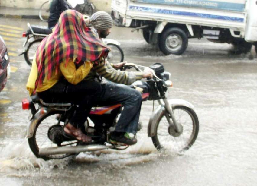 لاہور: شہر میں ہونیوالی بارش کے دوران دو موٹرسائیکل سوار ..