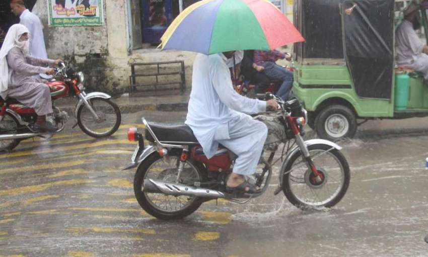 لاہور: شہر میں ہونیوالی بارش کے دوران ایک موٹر سائیکل سوار ..
