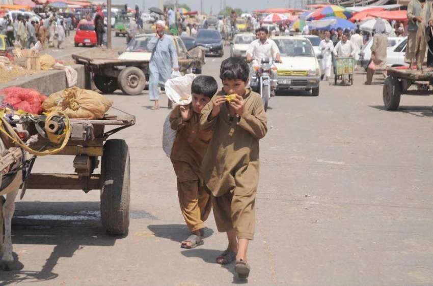 اسلام آباد: دو افغان بچے پھل کھاتے ہوئے منڈی روڈ سے گزر رہے ..