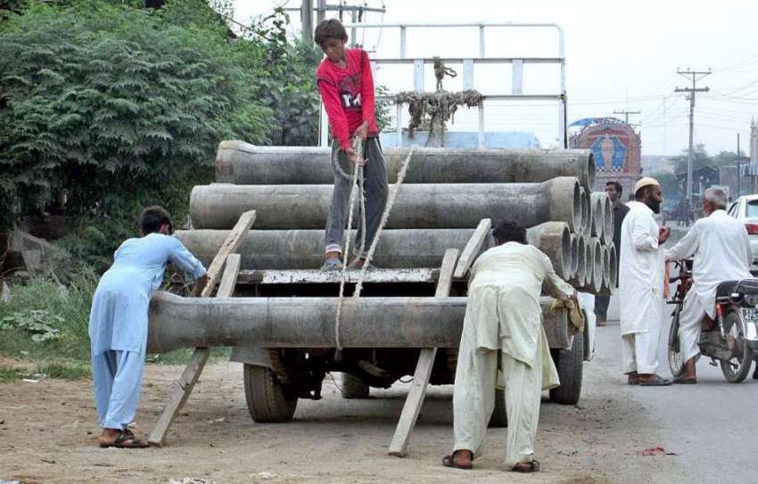 فیصل آباد: مزدور بھاری پائپ ٹرک پر لوڈ کر رہے ہیں۔