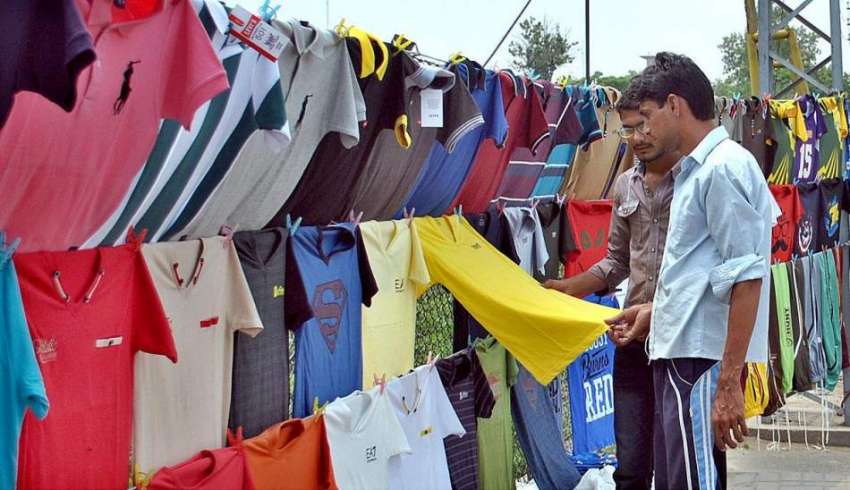 لاہور: محنت کش سڑک کنارے ٹی شرٹس فروخت کر رہا ہے۔