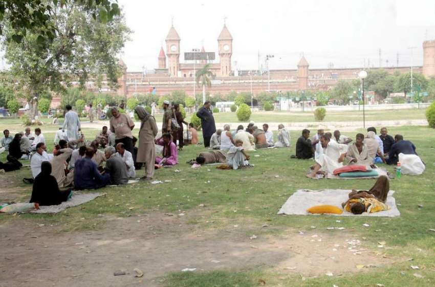 لاہور: شہری دوپہر کے وقت ریلوے اسٹیشن کے سامنے پارک میں درختوں ..
