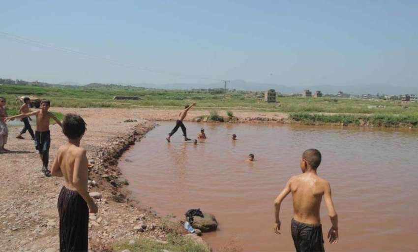راولپنڈی: افغان بچے گرمی کی شدت کم کرنے کے لیے بارشی پانی ..
