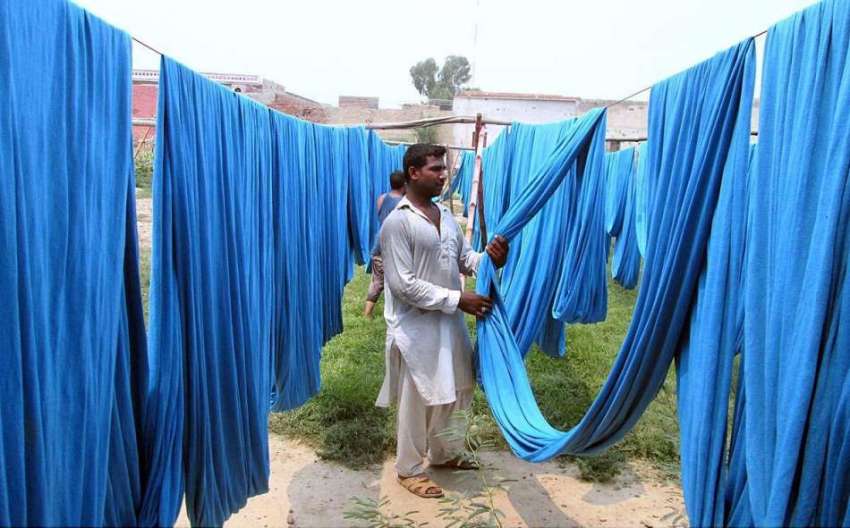 فیصل آباد: محنت کش کپڑا رنگنے کے بعد خشک کر رہا ہے۔