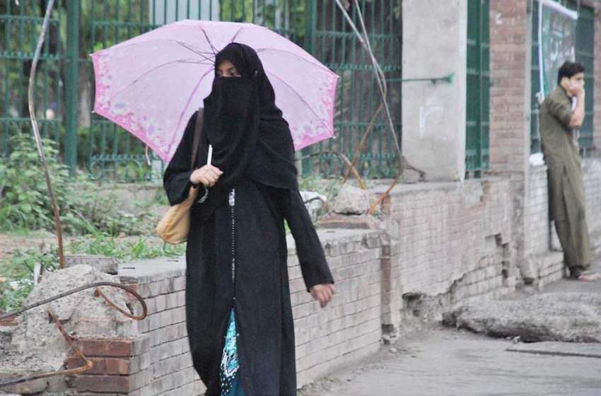 راولپنڈی: خاتون بارش سے بچنے کے لیے چھتری تانے جا رہی ہے۔