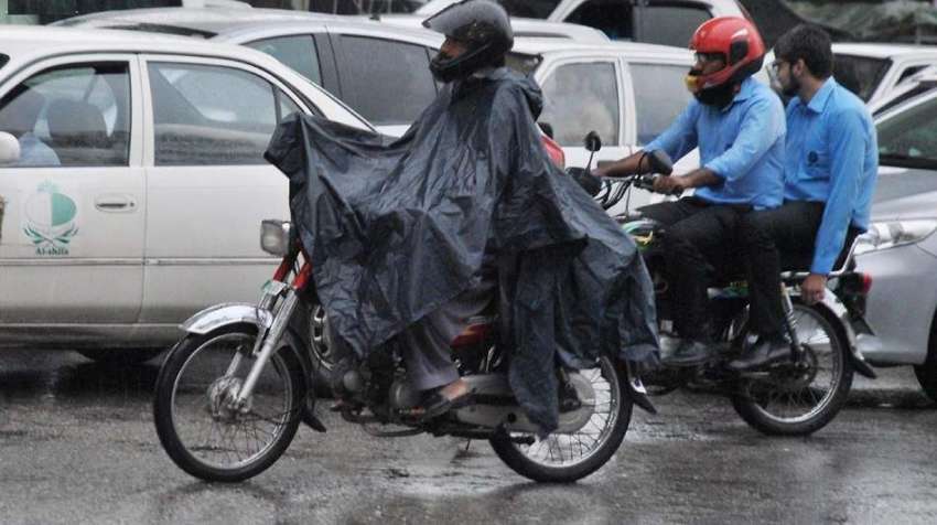 راولپنڈی: موٹر سائیکل سوار بارش سے بچنے کے لیے برساتی پہنے ..