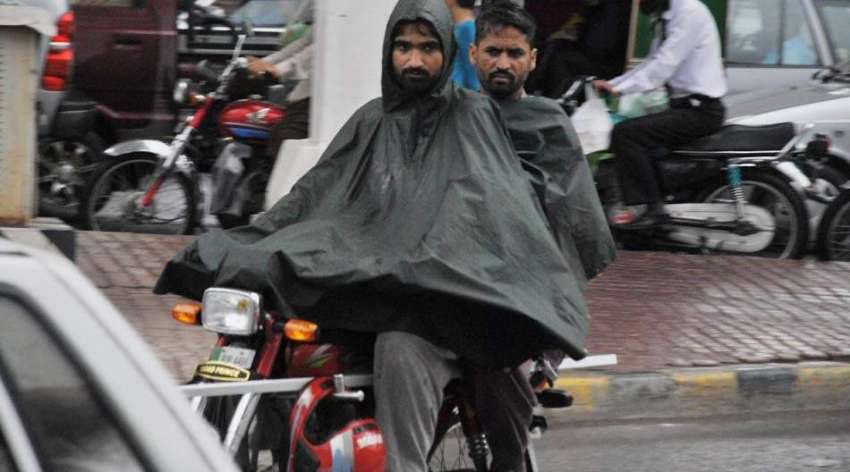 راولپنڈی: موٹر سائیکل سوار بارش سے بچنے کے لیے برساتی پہنے ..