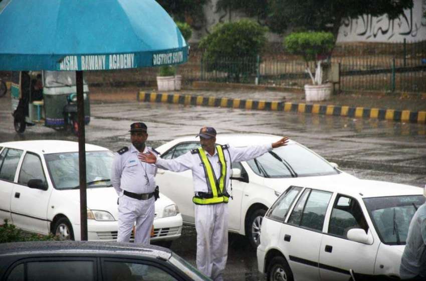 کراچی: بارش کے دوران ٹریفک وارڈن ٹریفک کنٹرول کرتے ہوئے۔