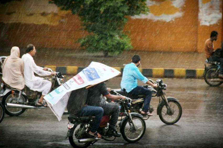 کراچی: موٹر سائیکل سوار موسلادھار بارش کے دوران اپنی منظر ..