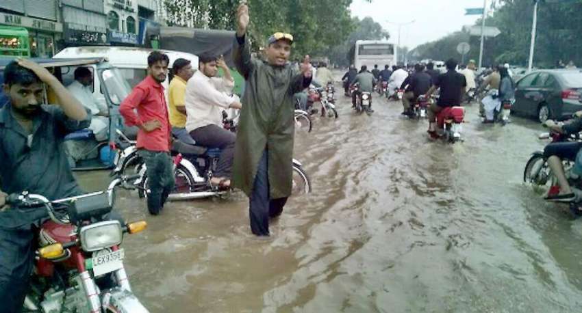 لاہور: ٹریفک وارڈن موسلا دھار بارش کے دوران ٹریفک کی روانی ..
