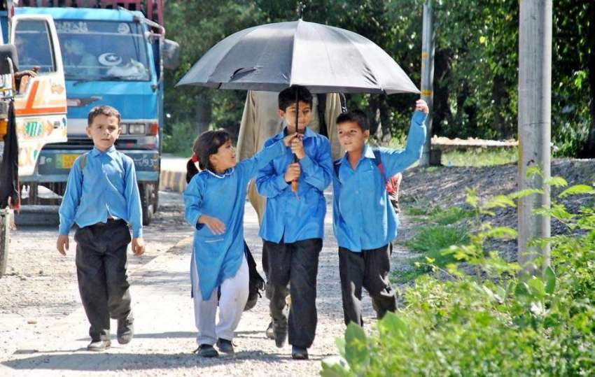 راولپنڈی: ننھے طلبہ دھوپ سے بچنے کے لیے چھتری تانے سکول سے ..