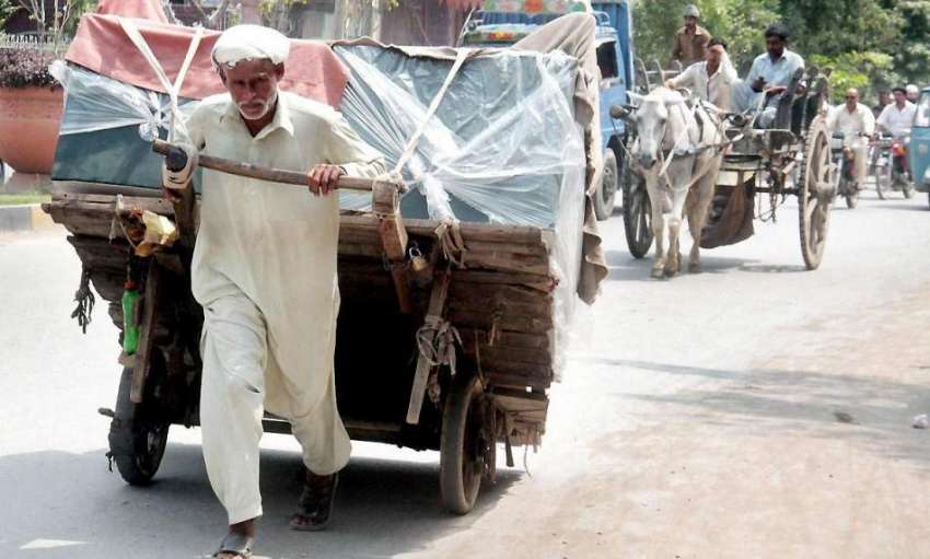 لاہور: ایک محنت کش ہتھ ریڑھی پر فرنیچر رکھے جا رہا ہے۔