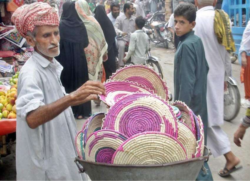 لاہور: ایک محنت کش بازار میں کھڑا گاہکوں کو متوجہ کرنے کے ..