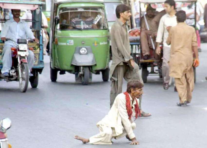 لاہور: ایک معذور شخص سڑک کراس کر رہا ہے۔