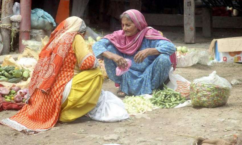 لاہور: سبزی منڈی میں ایک محنت کش خاتون سبزیاں فروخت کر رہی ..