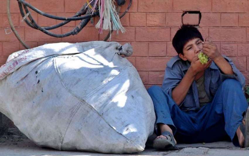راولپنڈی: خانہ بدوش بچہ فٹ پاتھ پر بیٹھا انگور کھا رہا ہے۔