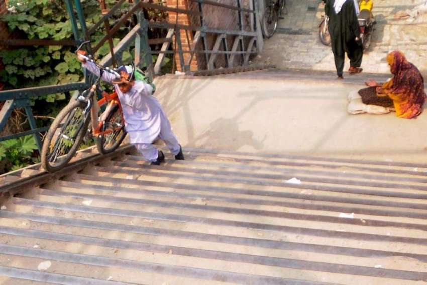 راولپنڈی: ایک طالبعلم اپنی سائیکل لیے صدر پل کی سیڑھیاں ..