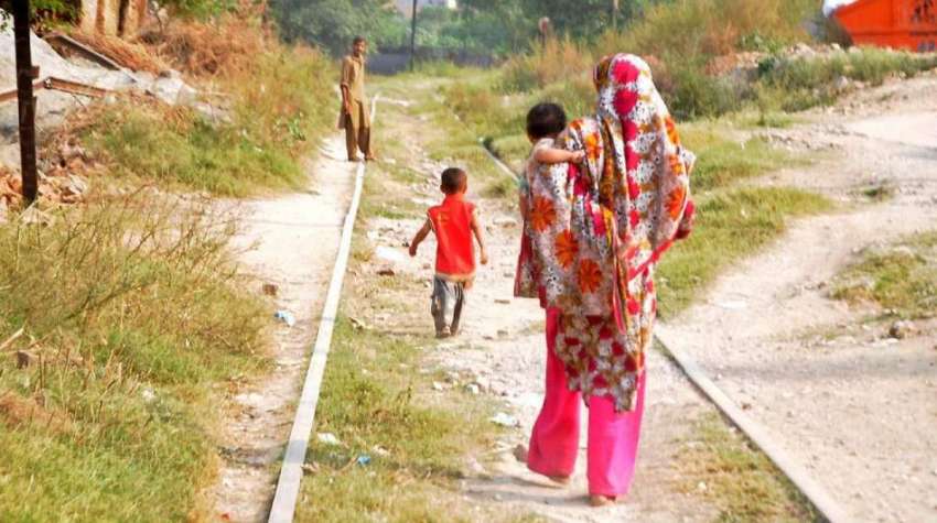 راولپنڈی: ایک خاتون اپنے بچوں کو لیے ریلوے لائن سے گزر رہی ..