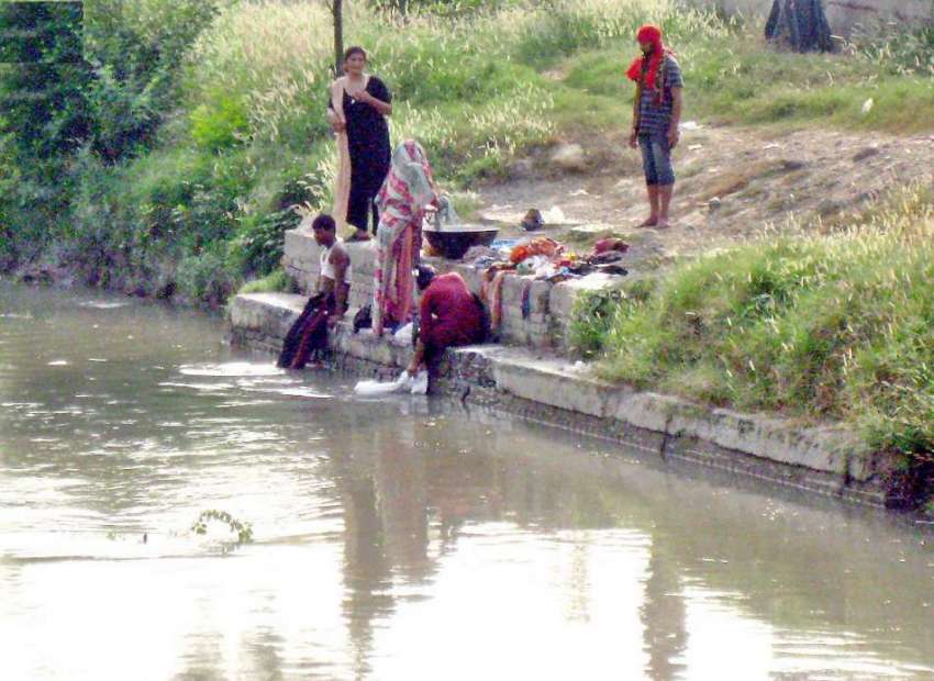 لاہور: نہر کنارے خانہ بدوش خواتین کپڑے دھو رہی ہیں۔